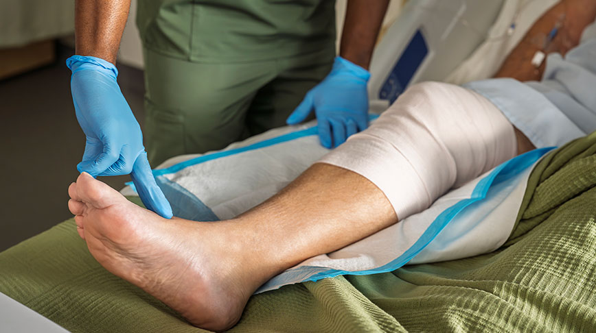 Close-up image of a healthcare professional wearing exam gloves and examining a patient's leg